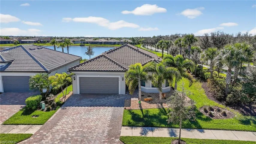 View of front facade with stucco siding, decorative driveway, a water view, a garage, and a front lawn