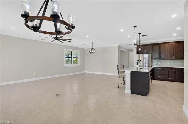 Kitchen with a kitchen bar, a kitchen island with sink, dark brown cabinetry, ornamental molding, and a chandelier