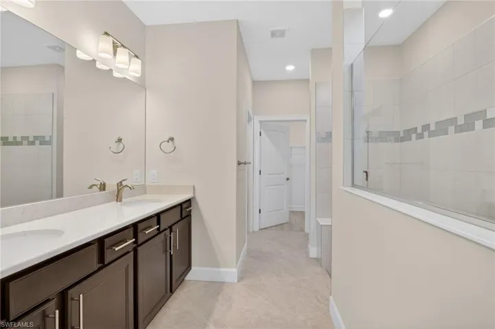 Full bathroom with a walk in shower, double vanity, and a walk in closet