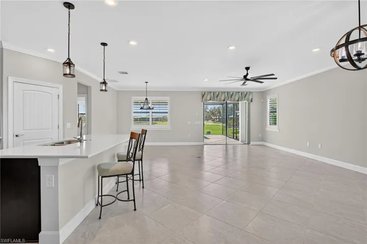 Kitchen with a chandelier, hanging light fixtures, recessed lighting, an island with sink, and a kitchen bar