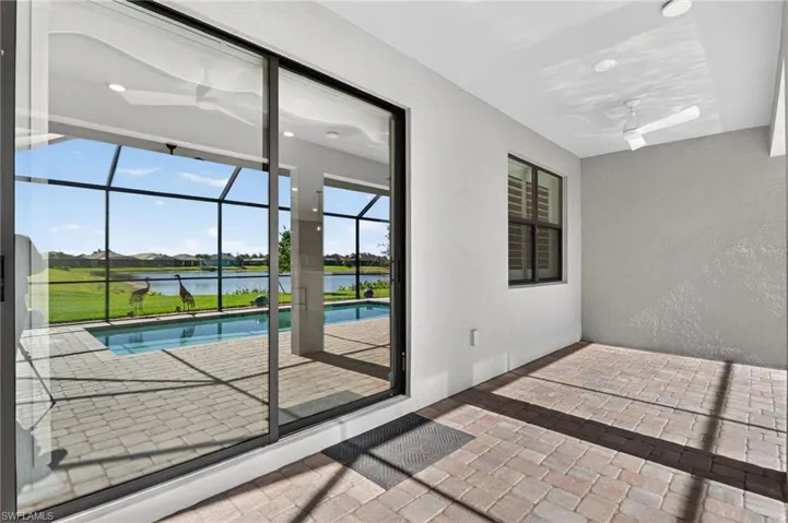 Doorway with a sunroom, a water view, a textured wall, stone tile flooring, and a residential view