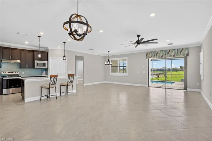 Kitchen featuring a chandelier, appliances with stainless steel finishes, light countertops, a kitchen bar, and ornamental molding