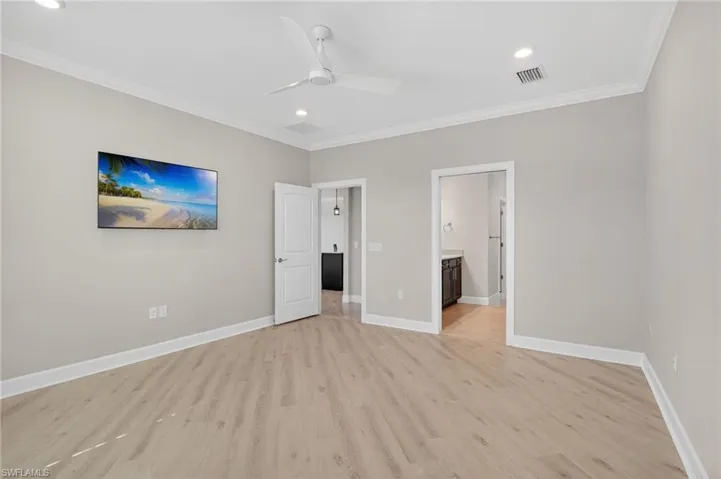 Unfurnished bedroom featuring light wood finished floors, ornamental molding, ceiling fan, recessed lighting, and connected bathroom