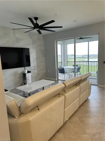 Living room featuring plenty of natural light, ceiling fan, and tile accent wall.