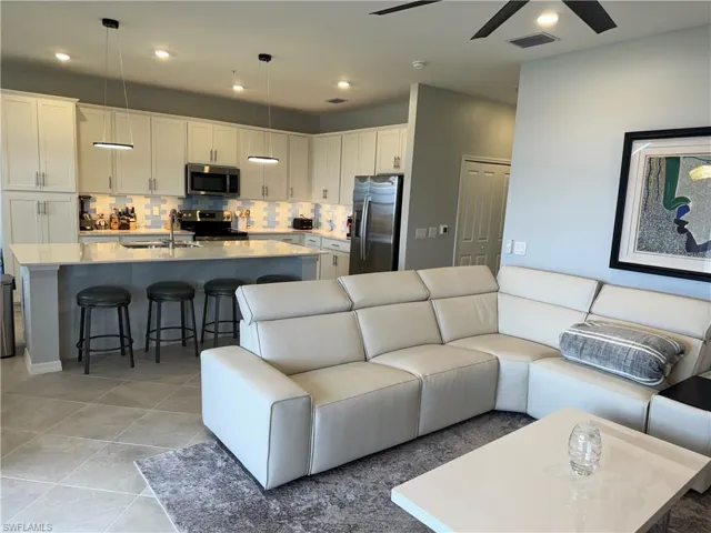 Living room with light tile patterned flooring, ceiling fan, and sink