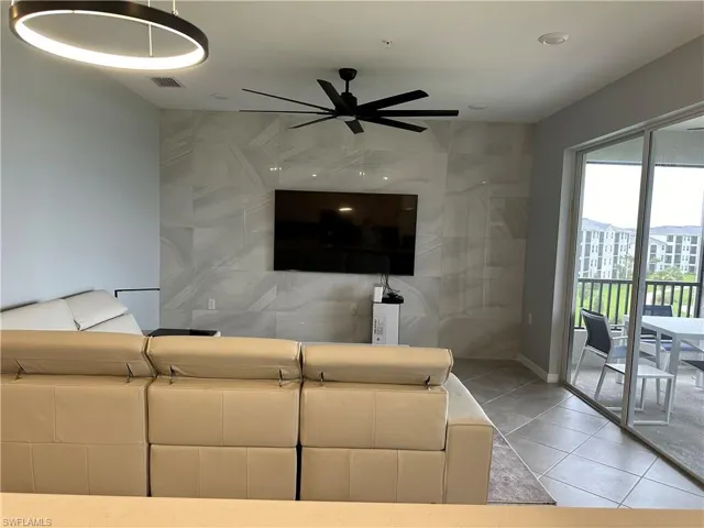 Living room with light tile patterned flooring and ceiling fan.