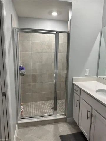 Master Bathroom featuring tile patterned flooring, a shower with shower door, and vanity