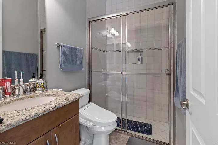 Bathroom with tile patterned flooring, vanity, a shower with door, and toilet