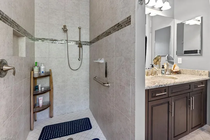 Bathroom with tile patterned floors, vanity, and tiled shower