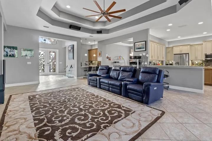 Tiled living room featuring french doors, a raised ceiling, and ceiling fan