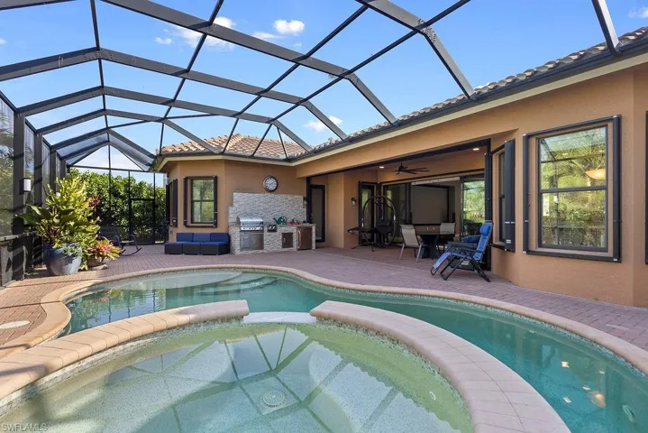 View of swimming pool featuring an outdoor kitchen, ceiling fan, a lanai, and an in ground hot tub