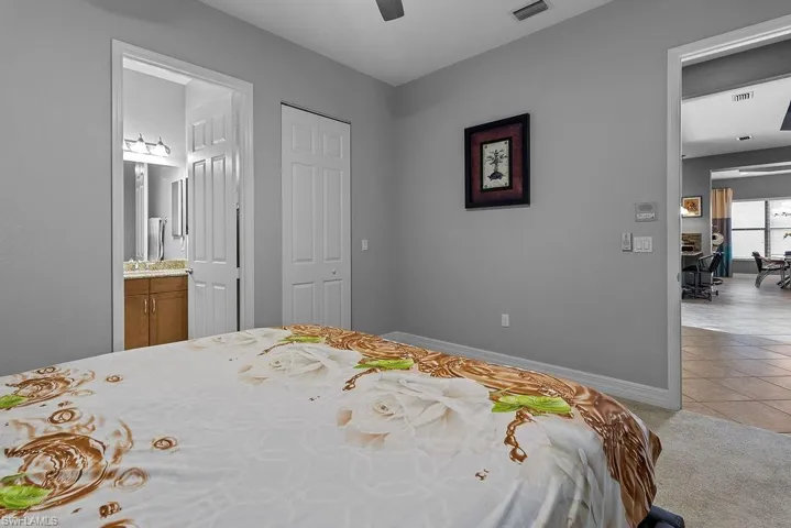 Carpeted bedroom with connected bathroom, a closet, and ceiling fan