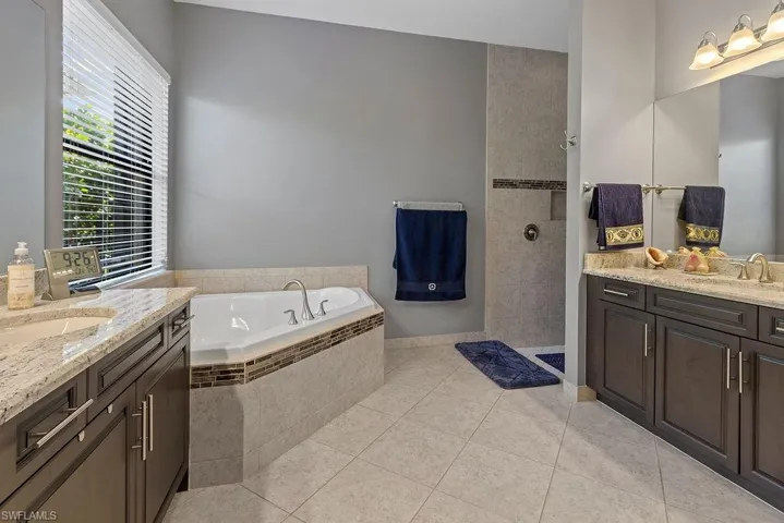 Bathroom featuring tile patterned floors, vanity, and shower with separate bathtub