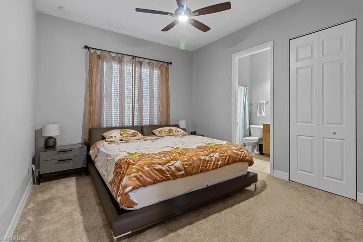Bedroom featuring connected bathroom, light colored carpet, and ceiling fan