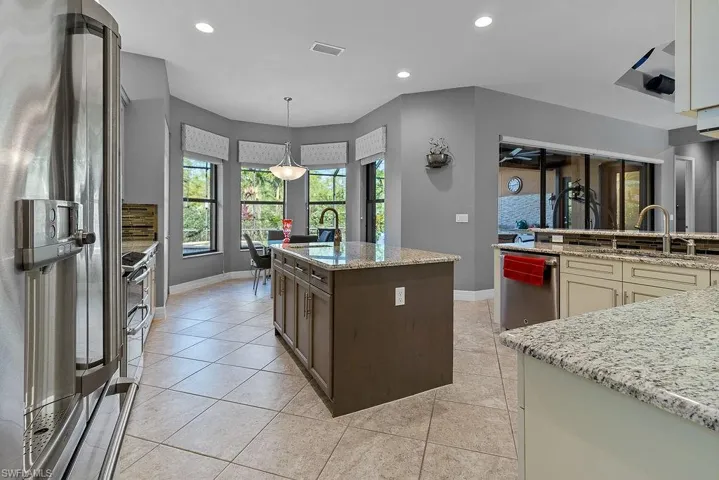 Kitchen with pendant lighting, a kitchen island with sink, cream cabinets, light tile patterned floors, and stainless steel appliances
