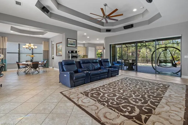 Tiled living room with a tray ceiling and ceiling fan with notable chandelier