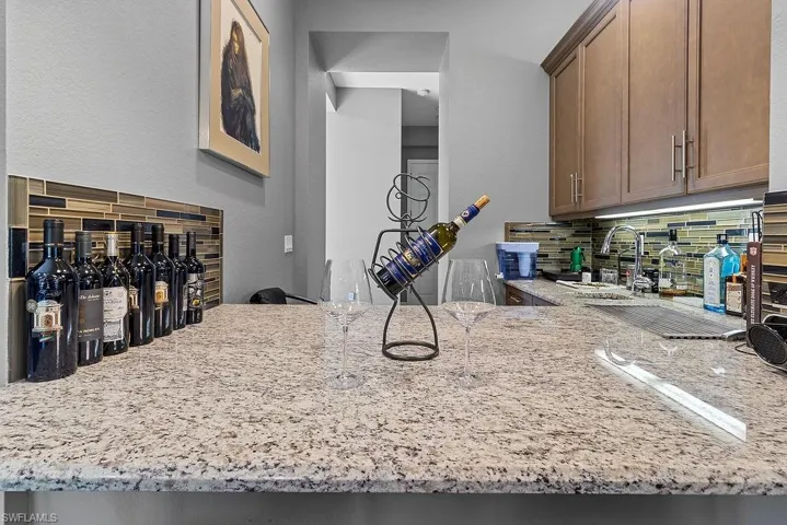 Kitchen featuring kitchen peninsula, decorative backsplash, sink, and light stone countertops