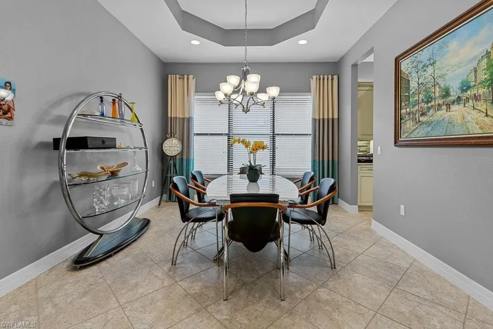 Tiled dining area with a notable chandelier and a raised ceiling