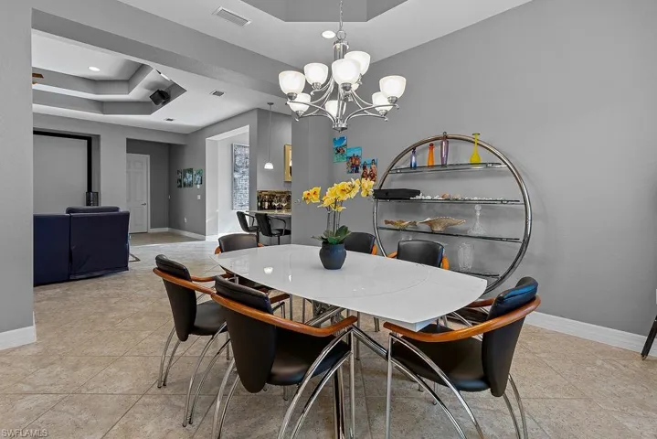 Tiled dining room with a raised ceiling and an inviting chandelier