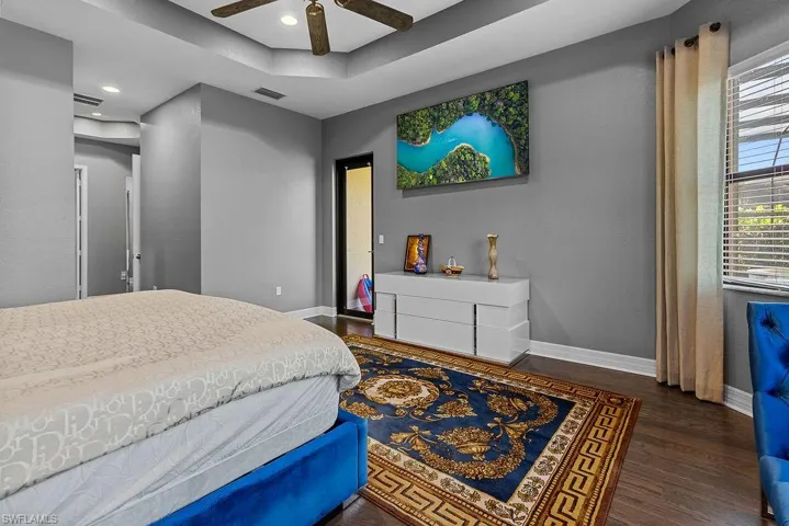 Bedroom featuring a tray ceiling, ceiling fan, and dark hardwood / wood-style flooring