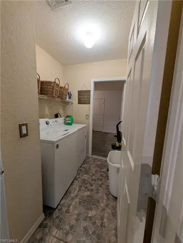 Dedicated laundry area featuring patterned tile flooring, a built-in wire shelf, and neutral wall tones