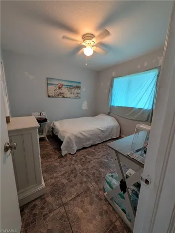 Room featuring patterned tile flooring, a window, and a ceiling fan with integrated lighting