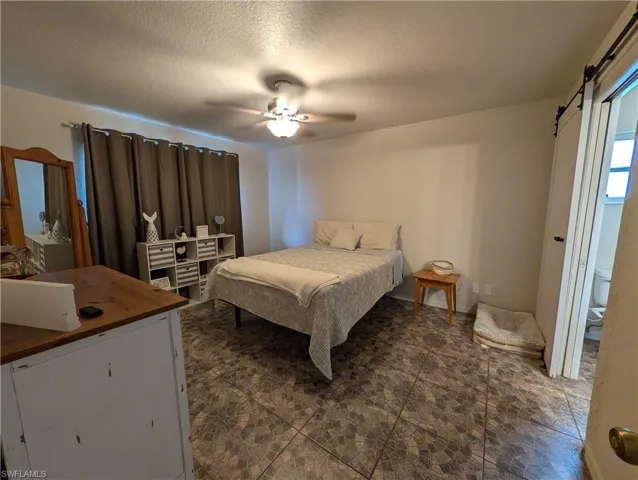 Spacious room featuring patterned tile flooring, a ceiling fan with integrated lighting, and dark window treatments