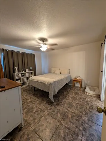 Room featuring patterned tile flooring, neutral wall tones, and a ceiling fan with integrated lighting