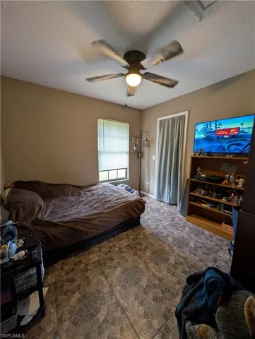 Room featuring decorative tile flooring, a window with blinds, and a ceiling fan