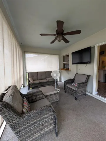 Enclosed porch featuring a ceiling fan, wall-mounted television, and textile window coverings
