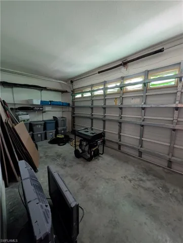 Spacious garage with concrete flooring, overhead garage door with multiple horizontal windows, and built-in shelving