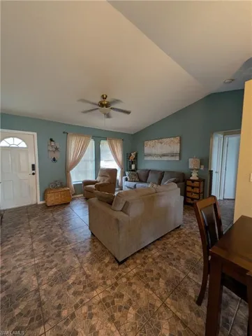 Spacious living area featuring vaulted ceilings, ceiling fan, and decorative tile flooring