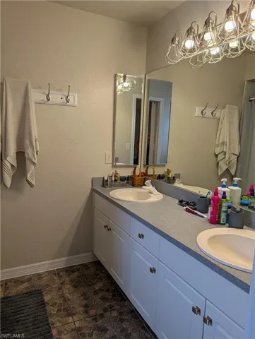 Double vanity with white cabinetry and chrome hardware, featuring two integrated sinks and a grey countertop