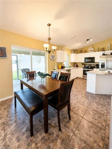 Dining area with mosaic tile flooring, a bronze-finish chandelier, and access to an outdoor screened patio via sliding glass doors