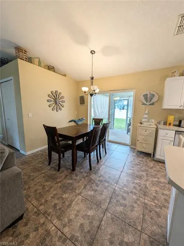 Spacious dining area featuring mosaic-patterned tile flooring, a contemporary chandelier, and sliding glass doors opening to an outdoor patio