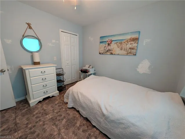 Room featuring patterned tile flooring, light blue wall paint, and a two-panel bi-fold closet door