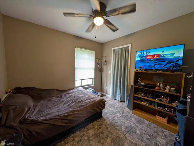 Interior room featuring a ceiling fan with integrated lighting, a window with blinds, and durable tile flooring