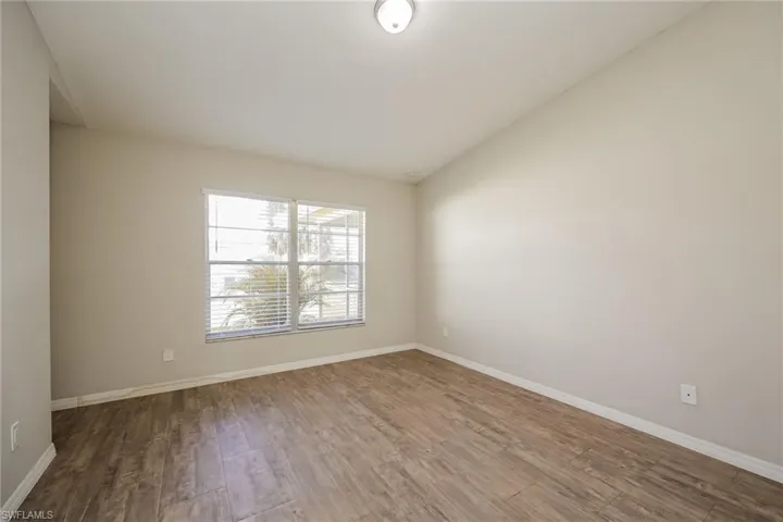 Empty room with lofted ceiling and hardwood / wood-style flooring