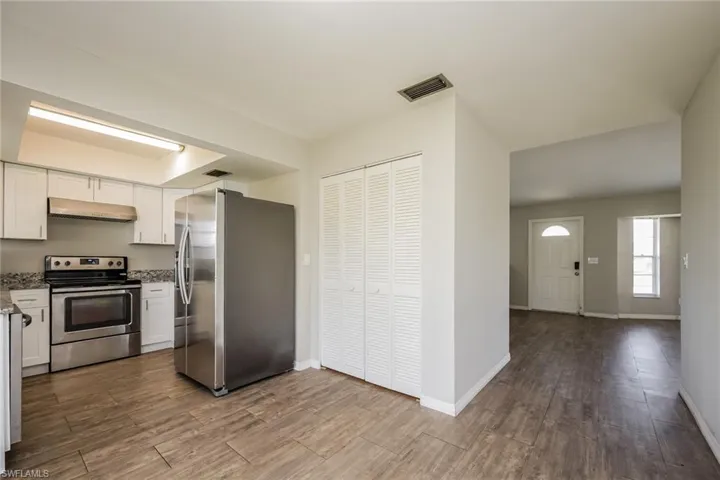 Kitchen with light stone counters, white cabinets, and appliances with stainless steel finishes
