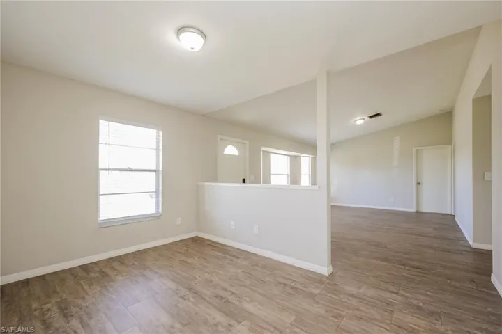 Empty room featuring hardwood / wood-style flooring and vaulted ceiling