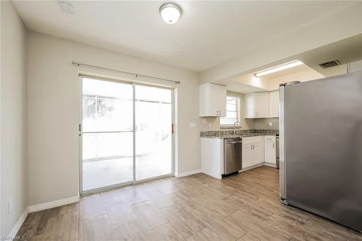Kitchen with white cabinets, appliances with stainless steel finishes, stone counters, and sink