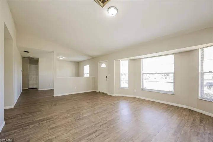 Empty room with vaulted ceiling and hardwood / wood-style flooring