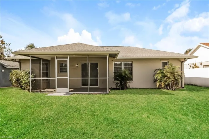 Rear view of property with a lawn and a sunroom