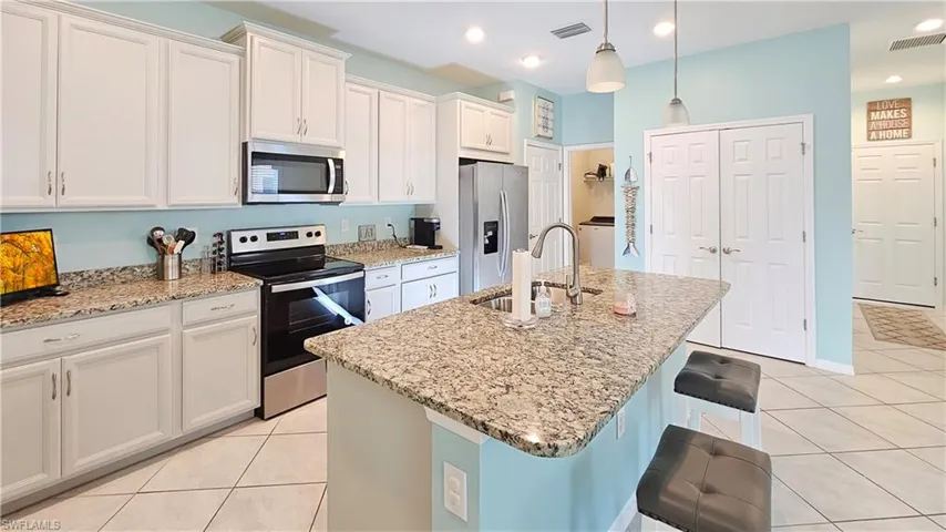 Kitchen featuring appliances with stainless steel finishes, a center island with sink, pendant lighting, and sink