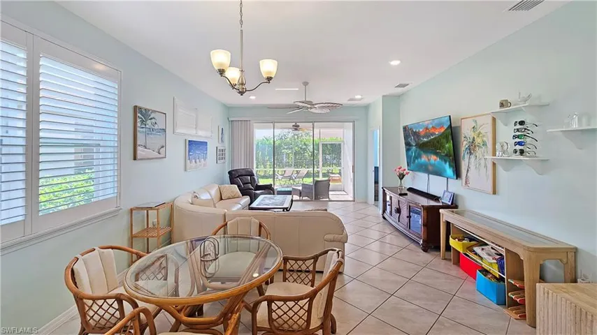 Tiled dining room featuring ceiling fan with notable chandelier
