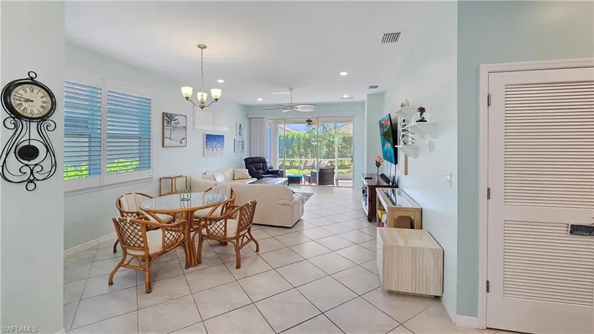Tiled dining space with ceiling fan with notable chandelier