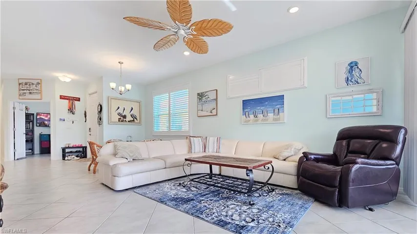 Tiled living room featuring ceiling fan with notable chandelier