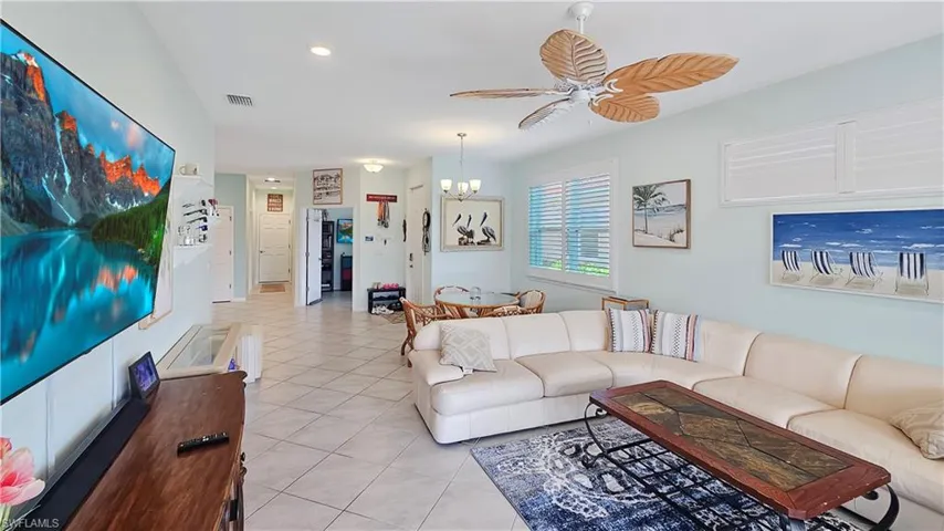 Tiled living room with ceiling fan with notable chandelier