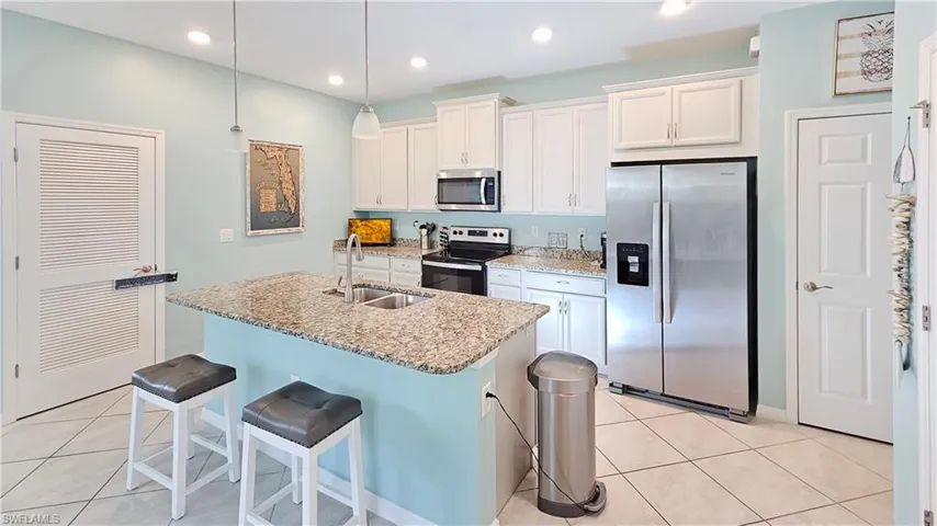 Kitchen with white cabinetry, a kitchen island with sink, sink, and stainless steel appliances