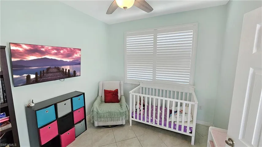 Tiled bedroom with ceiling fan and a nursery area